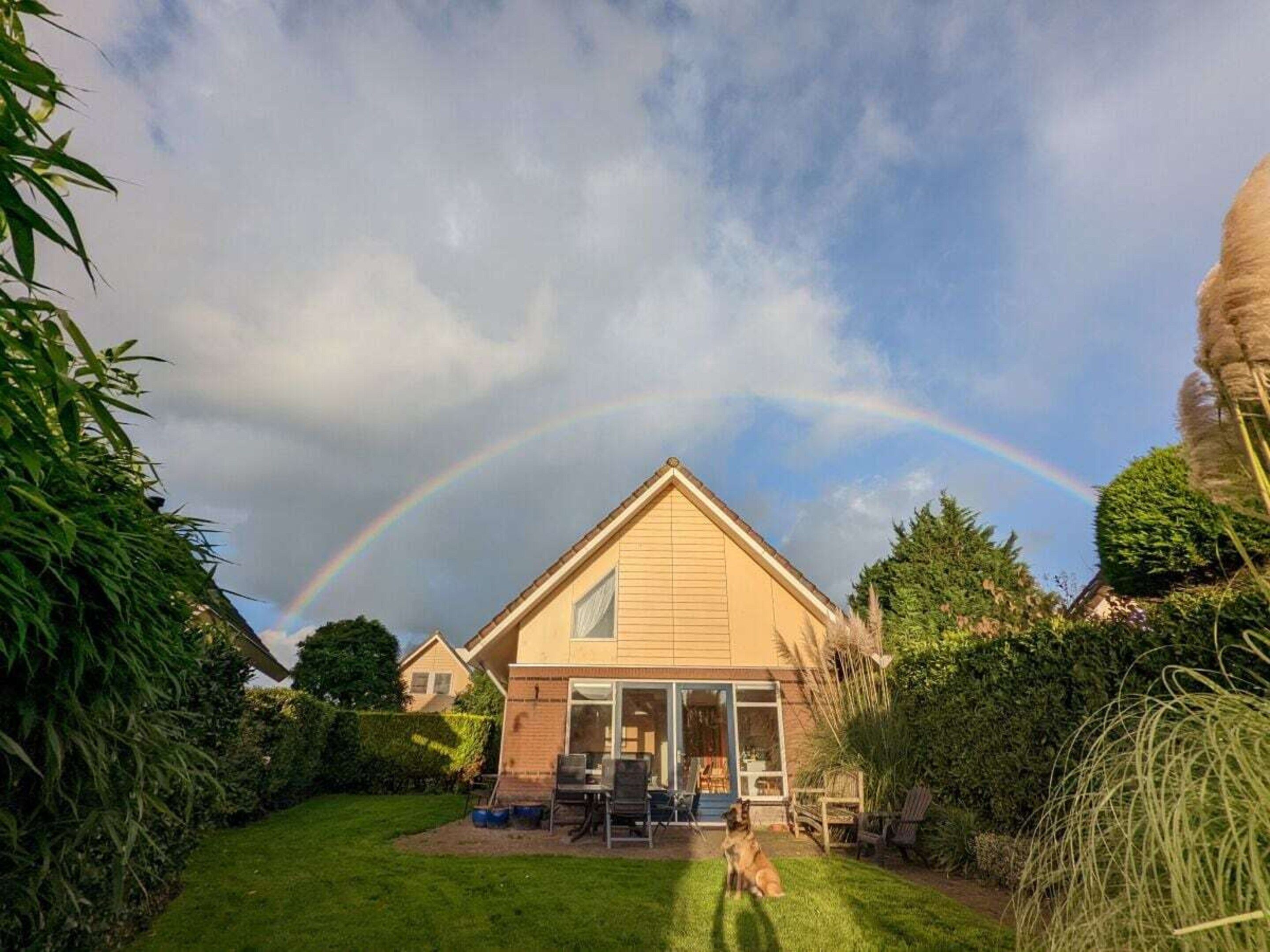 A house with a sloped roof, a covered patio area, and a lawn.