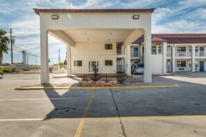 Una stazione di servizio con un edificio bianco, un'area per il rifornimento di carburante e una piccola fontana.