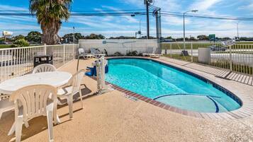 A swimming pool with a sunshade, lounge chairs, and a table.