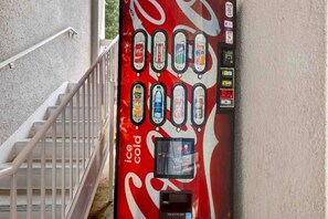 A vending machine with a Coca-Cola logo, offering various beverages including Coca-Cola, Sprite, and Fanta. - 1 Queen Bed | Smoking, Micfridge (Arlington)