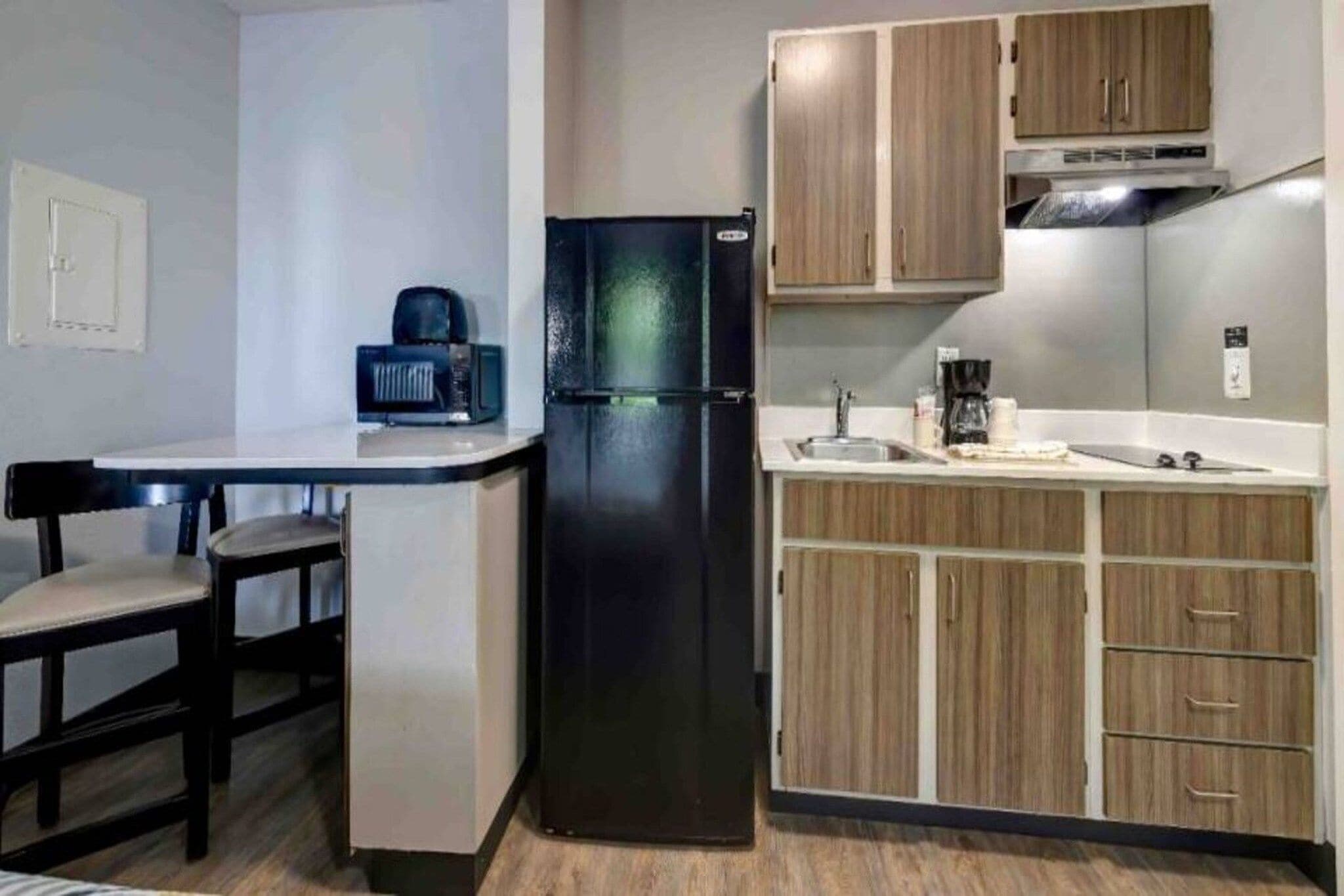 A compact kitchen with a refrigerator, a coffee maker, and wooden cabinets.