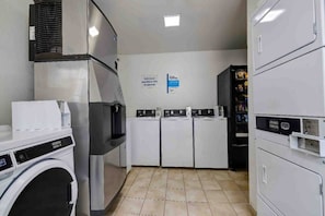 A laundry facility with a washing machine, dryers, and a vending machine. - 2 Full Beds | Smoking (Arlington)
