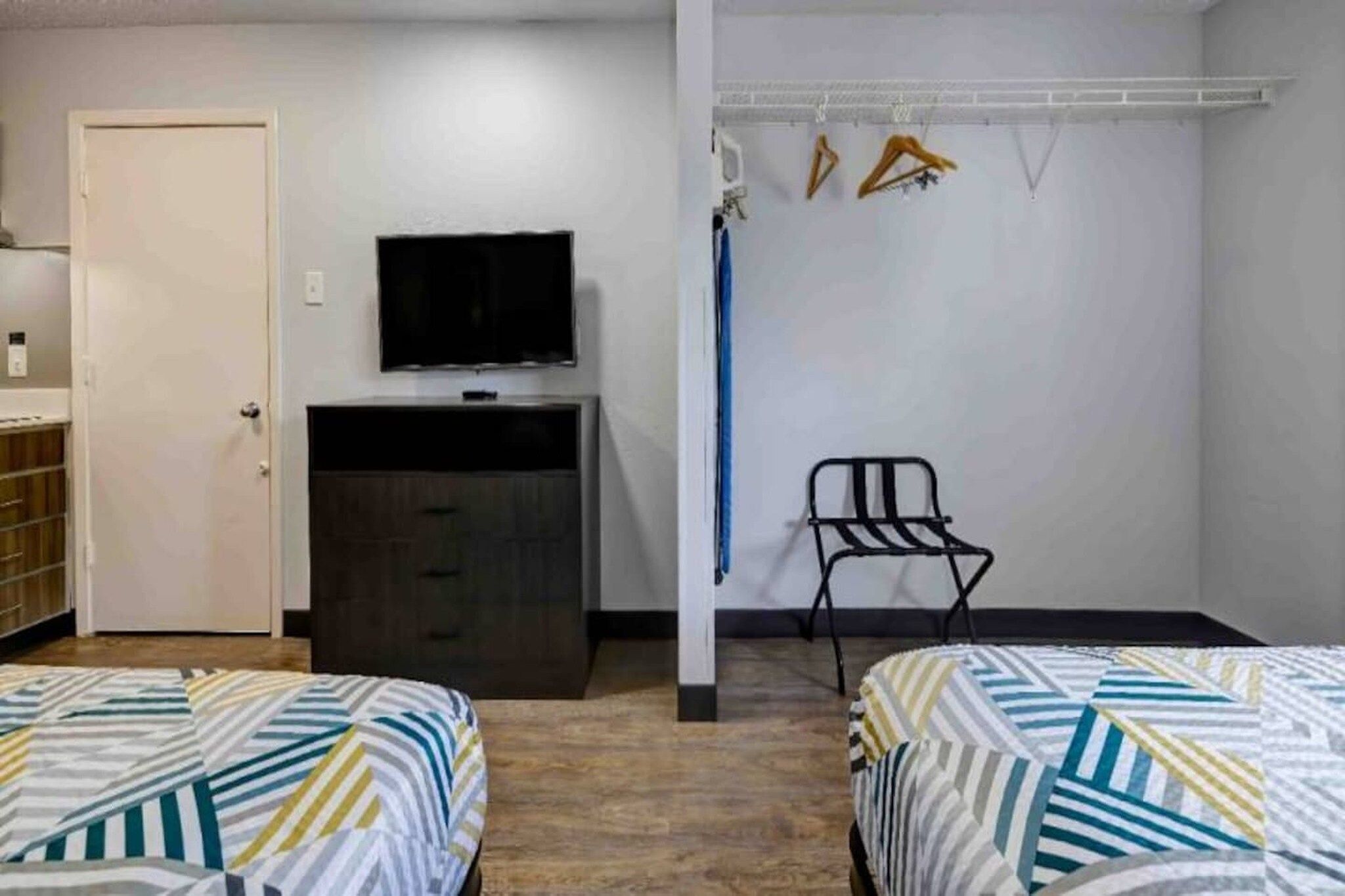 A room with two beds, a TV, a wardrobe, and a chair.