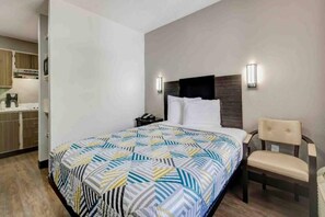 Ein Hotelzimmer mit einem Bett, einem Sessel, einem Nachttisch und einer Wandleuchte.