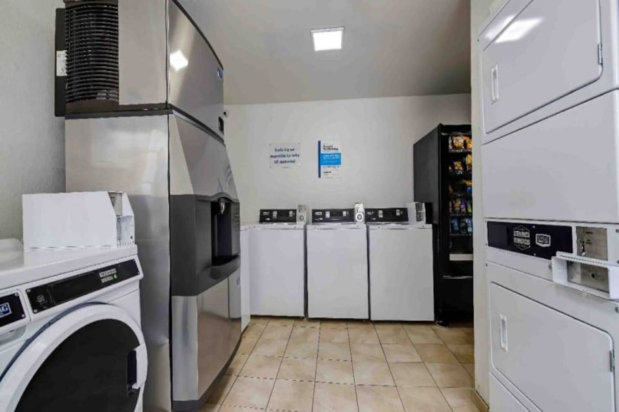 A laundry facility with a washing machine, dryers, and a vending machine.