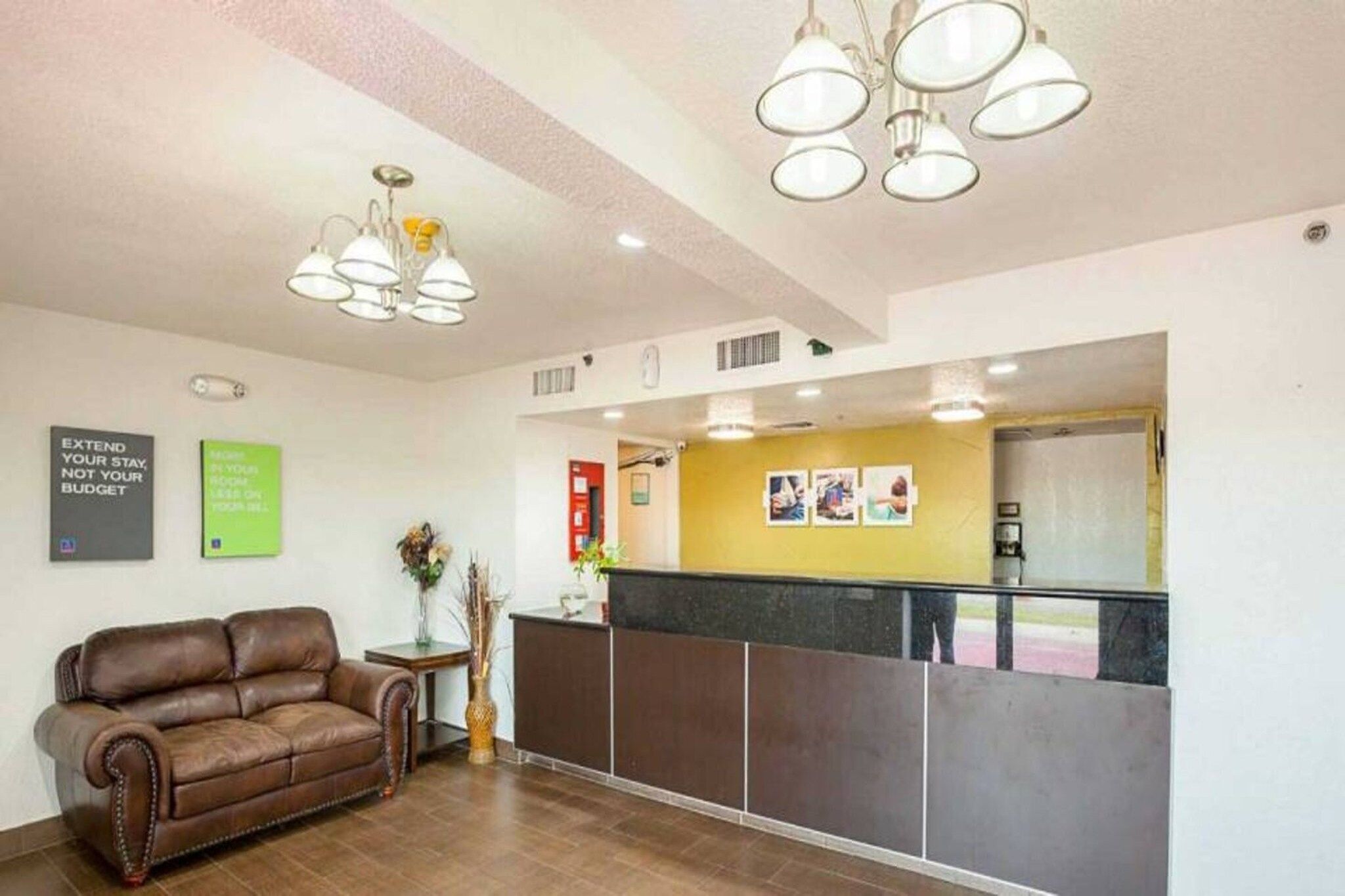 Ein Empfangsbereich mit einem braunen Ledersofa, einem kleinen Tisch mit einer Vase und einer Theke an einer gelben Wand.