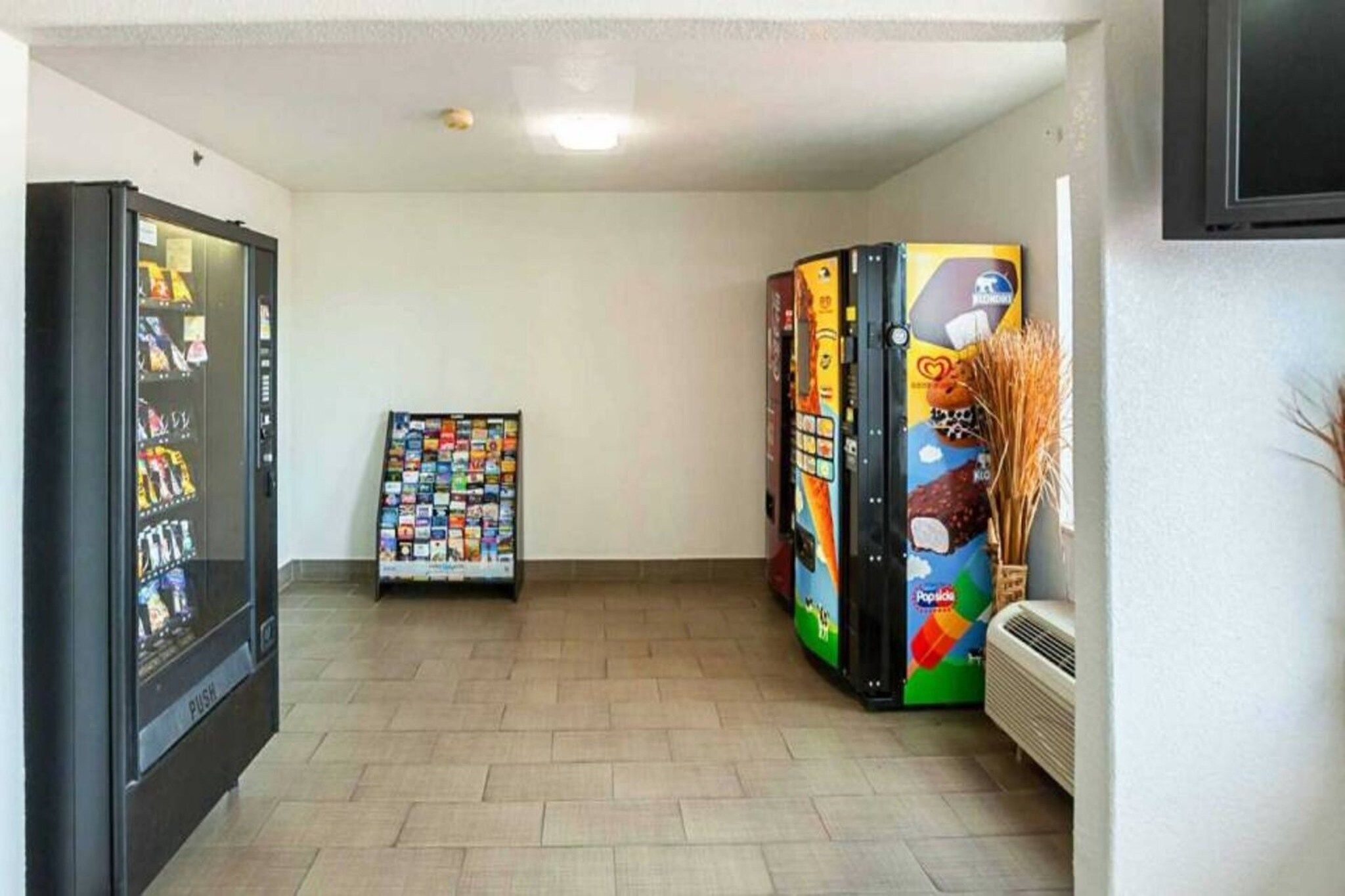 A hallway with vending machines, a wall-mounted air conditioner, and a tiled floor.