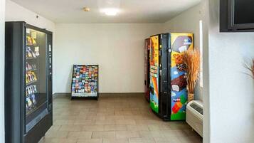 A hallway with vending machines, a wall-mounted air conditioner, and a tiled floor.