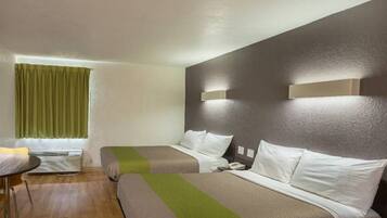 Ein Hotelzimmer mit zwei Betten, einem kleinen Tisch und einem Fenster mit Vorhängen.