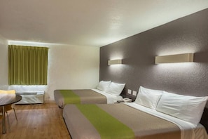 Ein Hotelzimmer mit zwei Betten, einem kleinen Tisch und einem Fenster mit Vorhängen.