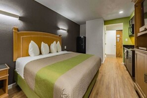 Une chambre d’hôtel équipée d’un lit, d’une table de chevet, d’un réfrigérateur et d’une kitchenette.