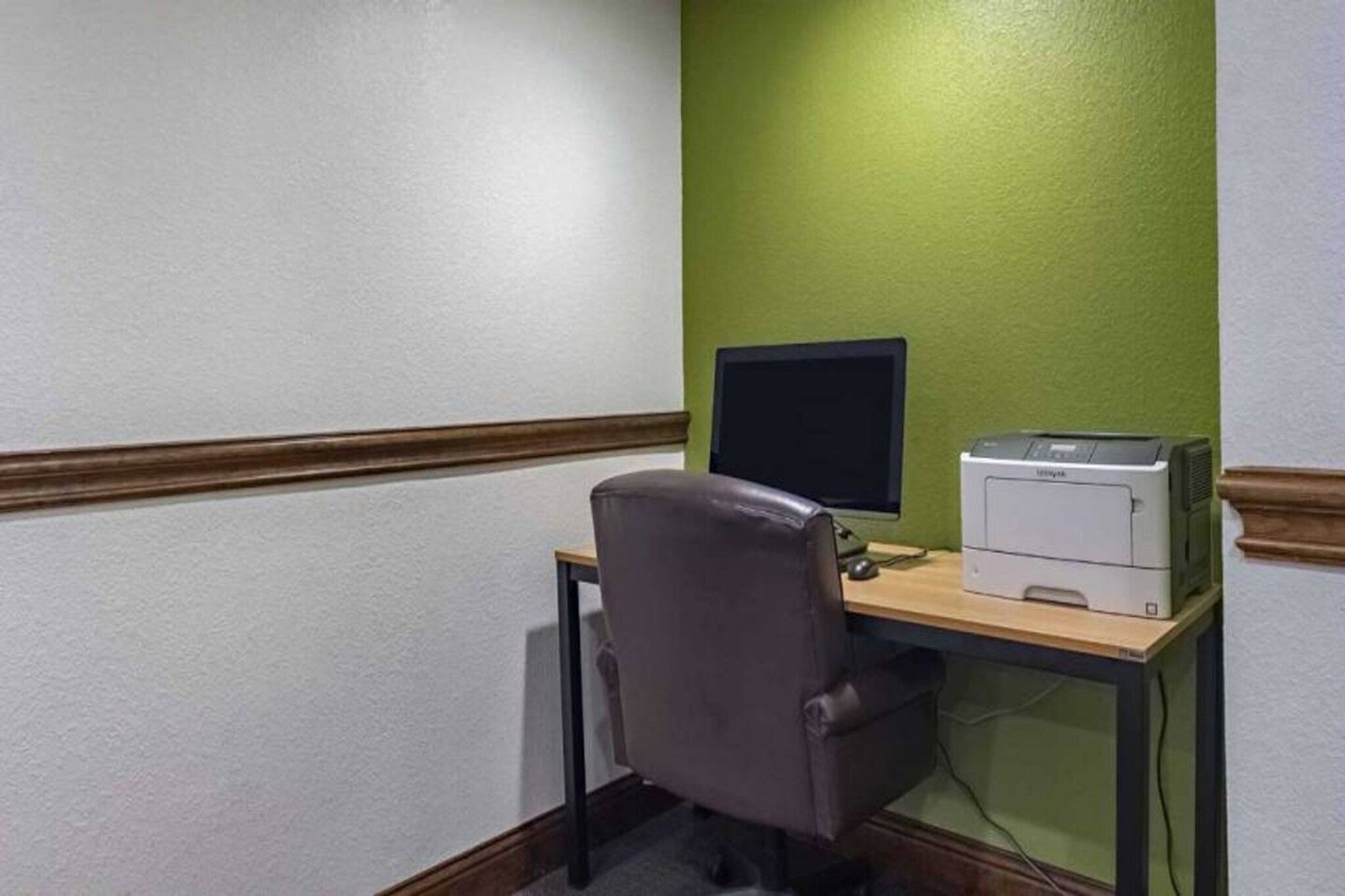 Un espai d'oficina petit amb escriptori, monitor d'ordinador i impressora.
