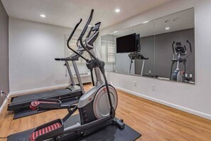 A home gym with treadmills, a stationary bike, and a mirrored wall. - 1 King Bed | Non-Smoking, Kitchen (Plano)