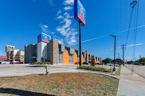 A commercial building with a prominent '6' sign, a parking lot, and a grassy area with a fire hydrant. - 2 Full Beds | Non-Smoking, Kitchen (Plano)