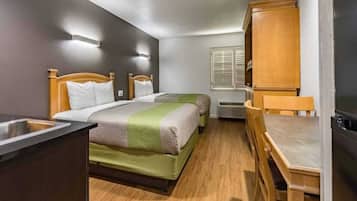 A compact room with a bed, a small table, and a kitchenette area.