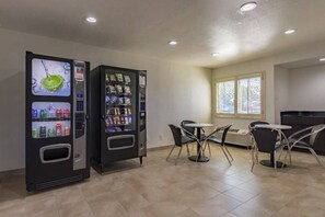 A room with two vending machines, a table, and four chairs. - 1 King Bed|Mobil Access Tub NS Kitchen (Plano)