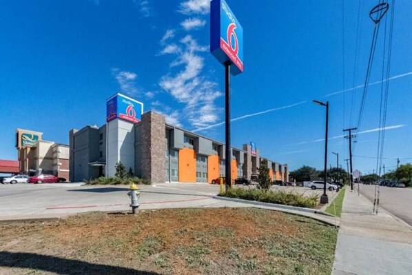 A commercial building with a prominent '6' sign, a parking lot, and a grassy area with a fire hydrant. - 2 Full Beds|Smoking| Kitchen (Plano)