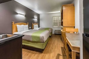 A compact room with a bed, a small table, and a kitchenette area. - 2 Full Beds|Smoking| Kitchen (Plano)
