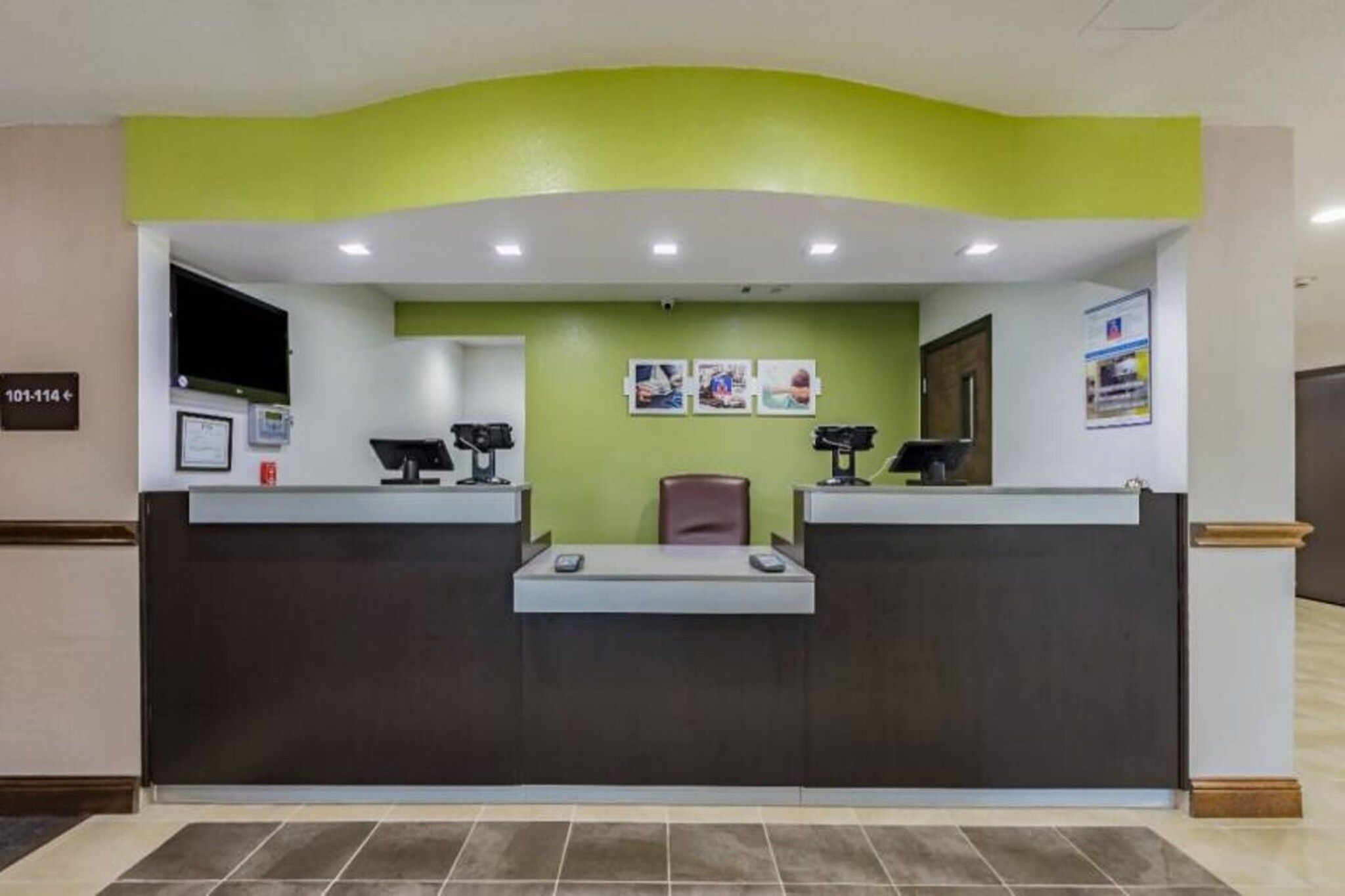 A reception desk with a green accent wall, a counter, and a chair.