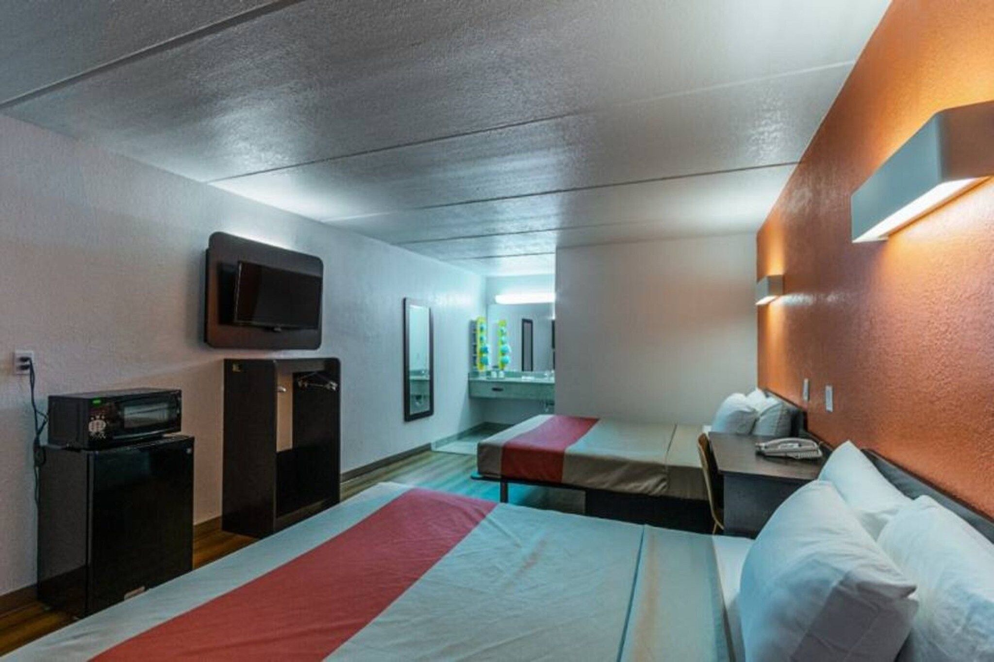 Habitación de hotel con dos camas, televisión, microondas y un escritorio pequeño.