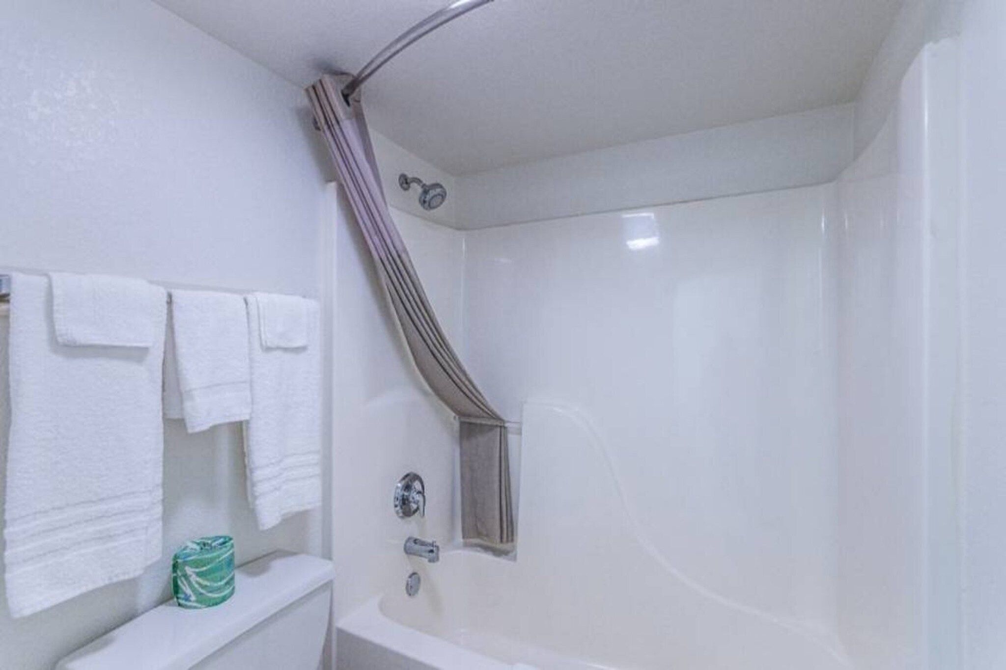 Un baño con bañera, cortina de ducha y toallero con varias toallas.