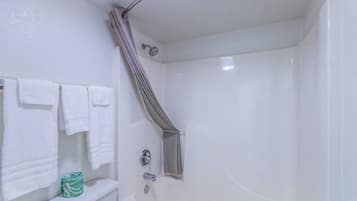 Un baño con bañera, cortina de ducha y toallero con varias toallas.