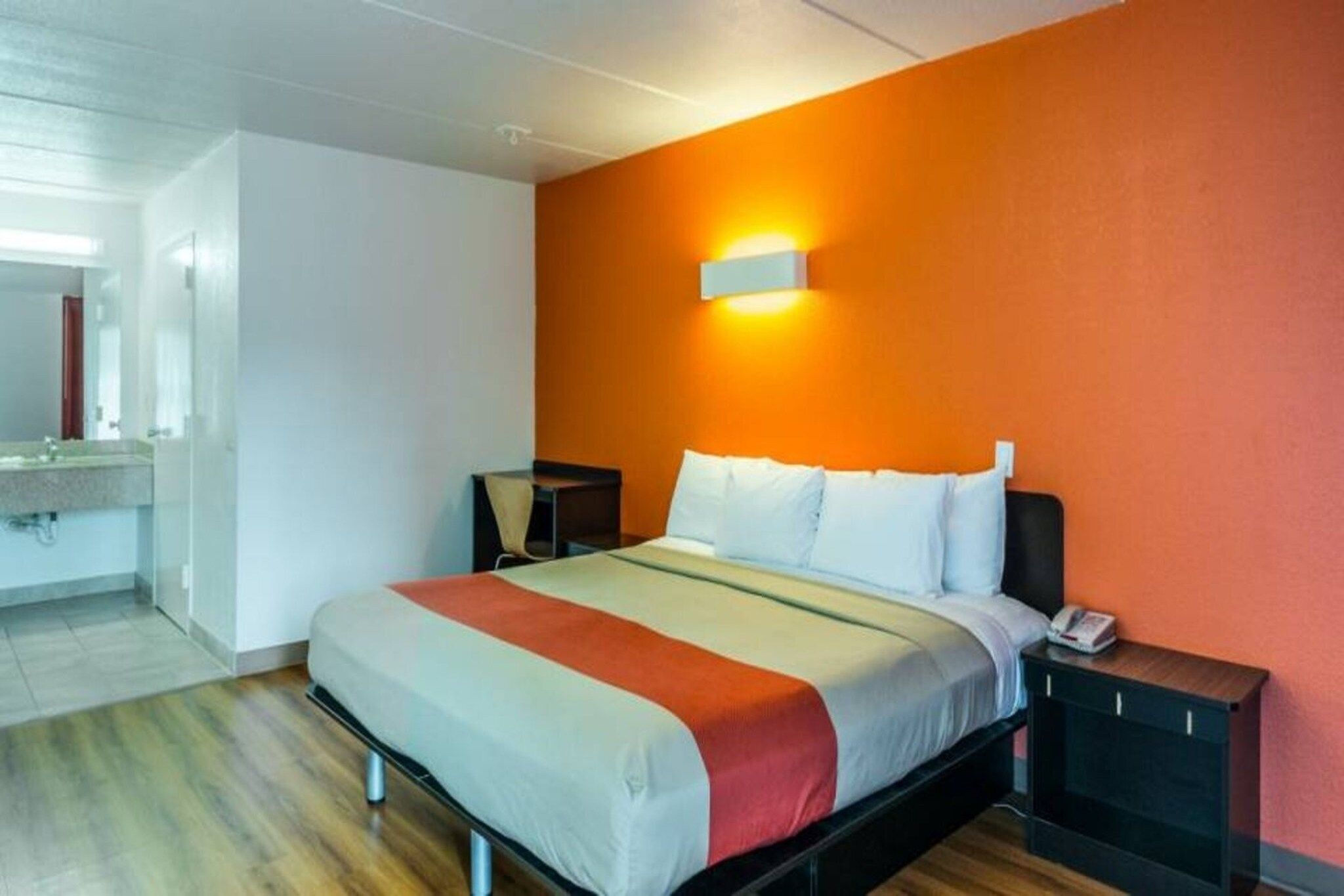 Una habitación de hotel con una cama, mesitas de noche y un baño a la vista.