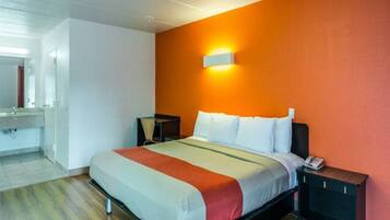 Una habitación de hotel con una cama, mesitas de noche y un baño a la vista.