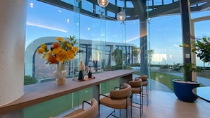 A modern bar area with a glass railing, a vase of yellow flowers, and a decorative bird statue. - New 1 BR Condo with Seaview (BW287) (Hua Hin)