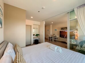 A hotel room with a bed, a desk, a chair, and a large window with curtains. - New 1 BR Condo with Seaview (BW287) (Hua Hin)