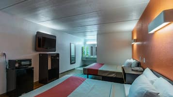 A hotel room with two beds, a TV, a microwave, and a small desk.