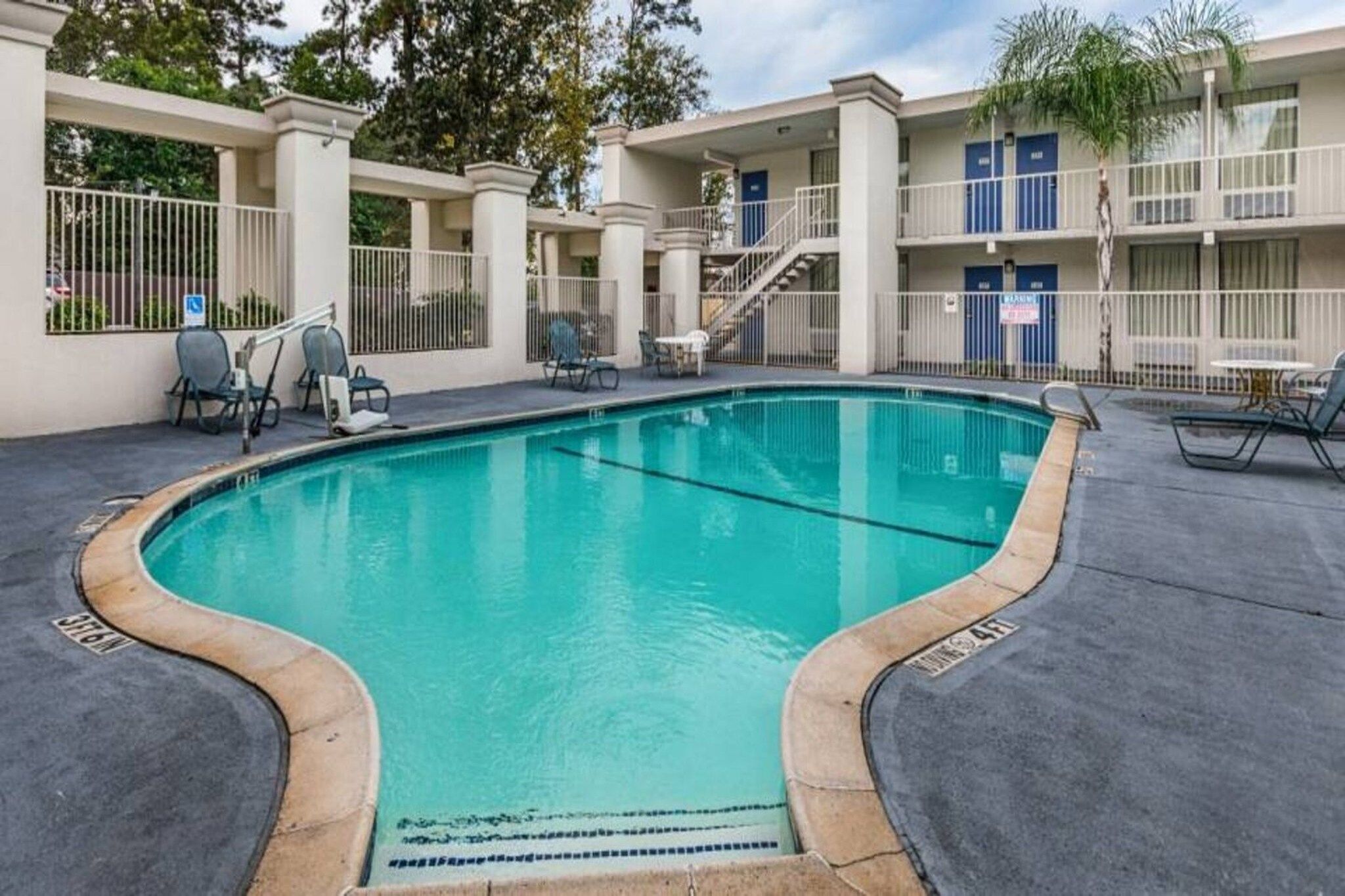 A swimming pool with lounge chairs and a covered area with tables and chairs.