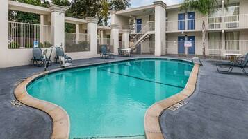 A swimming pool with lounge chairs and a covered area with tables and chairs.