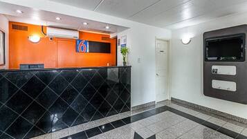 A reception area with a black marble counter, a number 6 sign, a white door, and a wall-mounted information kiosk.