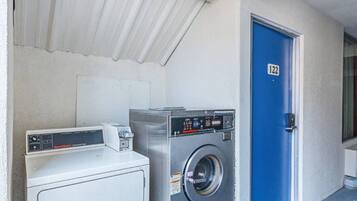 A laundry area with a white dryer, a front-loading washing machine, and a blue door marked with the number 122.