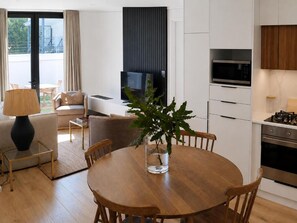 A modern kitchen with a microwave, oven, and a dining area with a round table and chairs. - Penthouse at Aan de Meul (Stellenbosch)