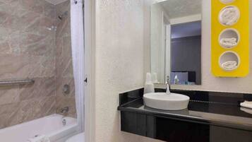 A bathroom with a bathtub, a sink, and a mirror.