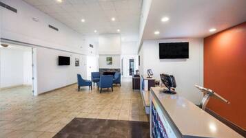 A spacious reception area with a counter, seating, and a large screen.