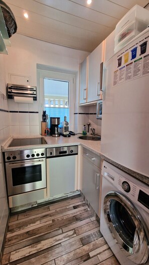 A compact kitchen with a built-in oven, microwave, and washing machine. - Brüggemann Bummelallee Vacation Rental (Bad Harzburg)