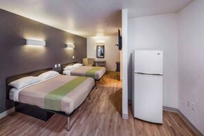 A hotel room with two beds, a small table, a chair, a flat-screen TV mounted on the wall, and a white refrigerator. - 2 FULL BEDS | NON-SMOKING, KITCHEN (Irving TX)