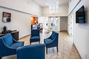 A hotel lobby with a reception desk, seating area, and a television mounted on the wall. - 2 FULL BEDS | SMOKING, KITCHEN (Irving TX)