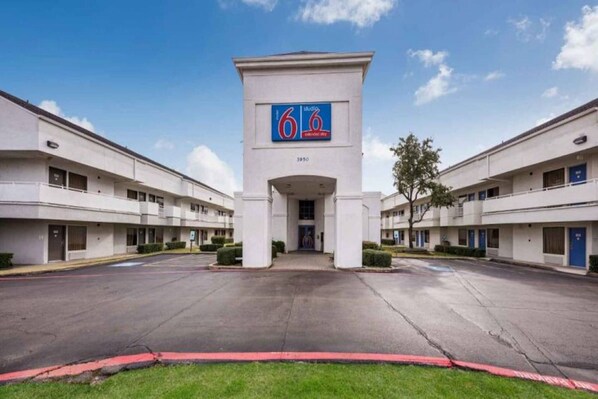 A building with a central entrance, a sign with the number '6', and a flat facade with multiple windows. - 2 FULL BEDS | SMOKING, KITCHEN (Irving TX)