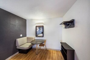 A compact room with a sofa, a small round table, and a wall-mounted TV. - 2 FULL BEDS | SMOKING, KITCHEN (Irving TX)