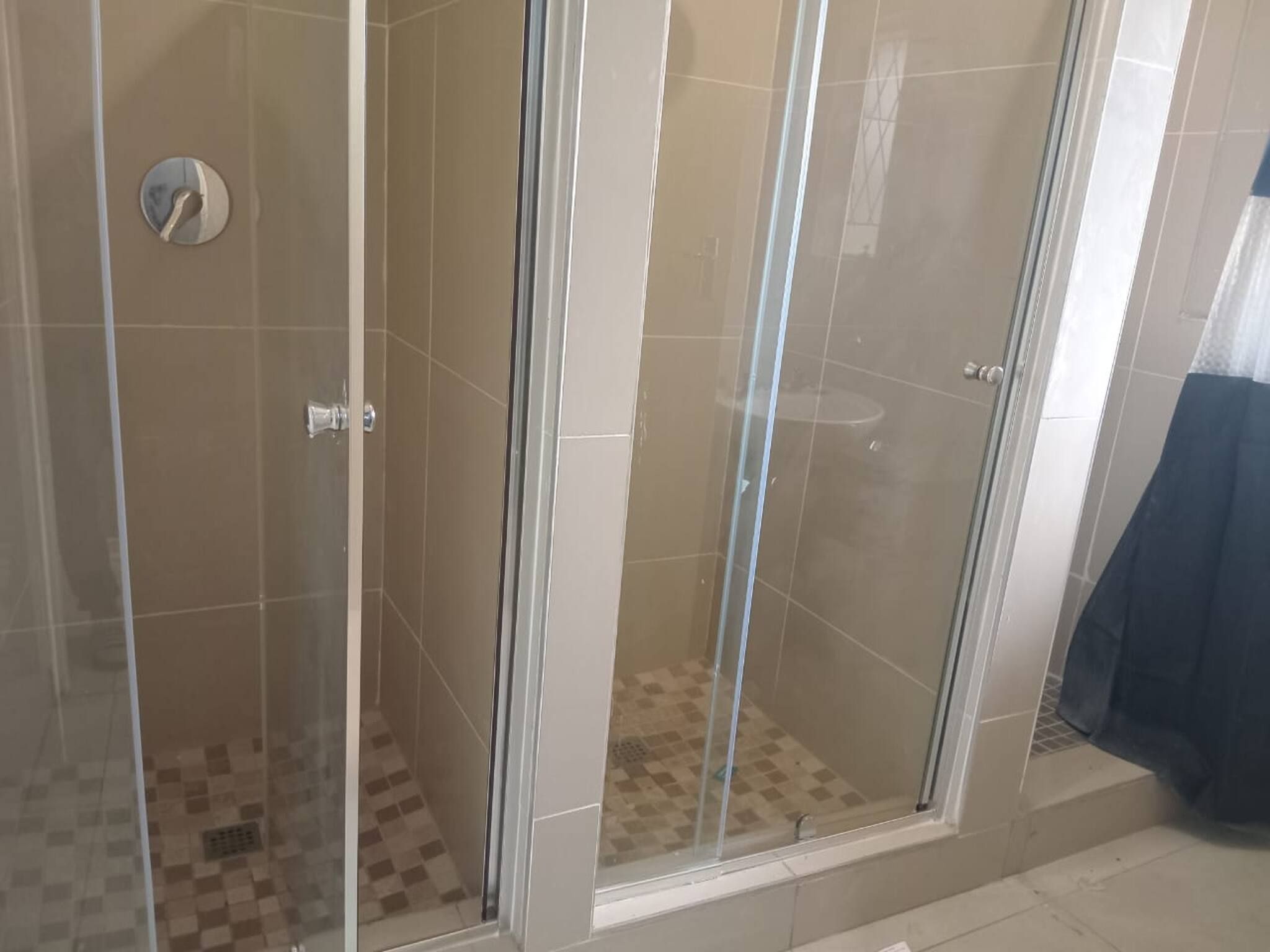 A glass-enclosed shower area with tiled walls and a checkered floor pattern.