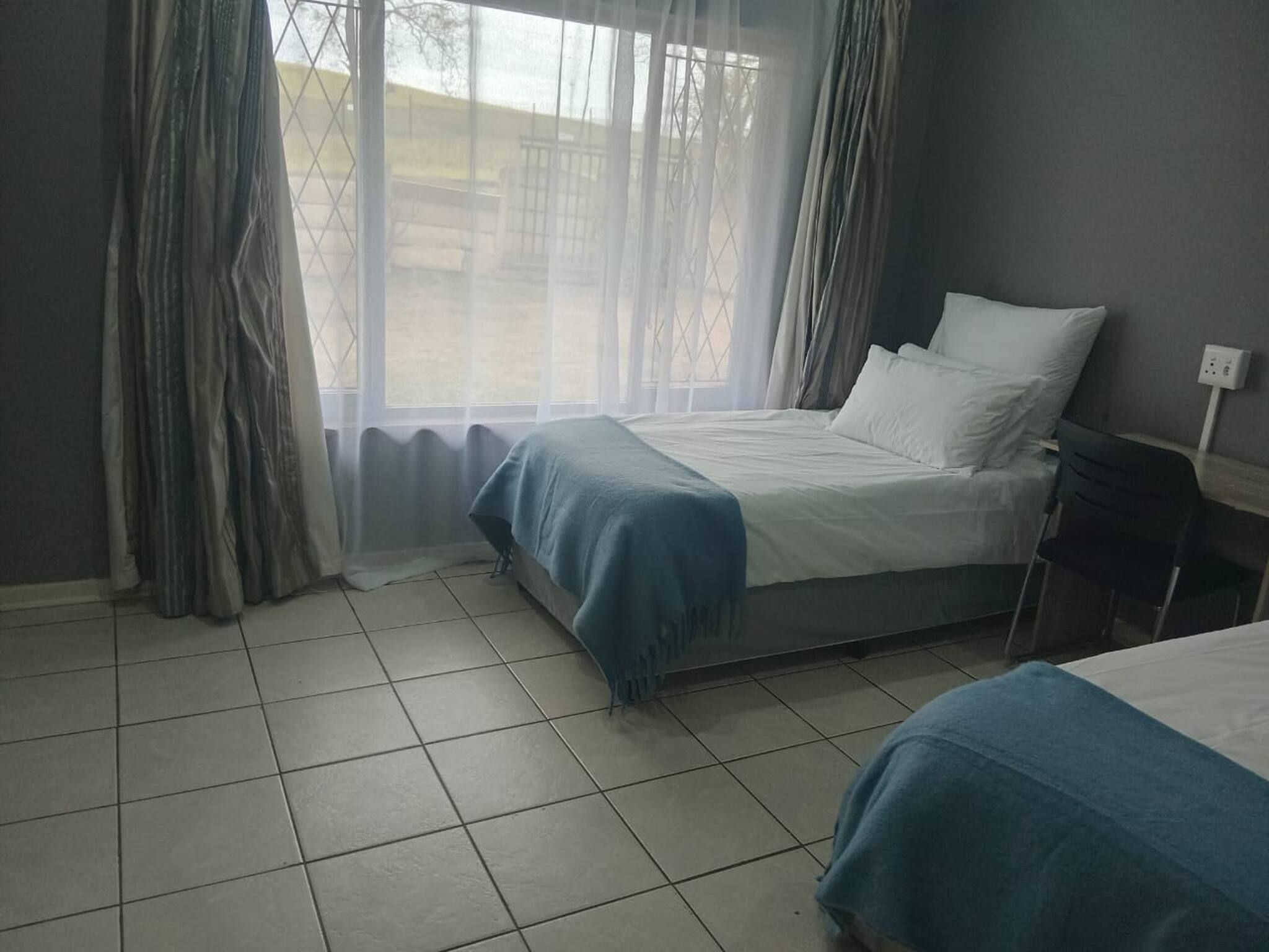Ein Hotelzimmer mit Bett, Nachttisch und einem Vorhangfenster.