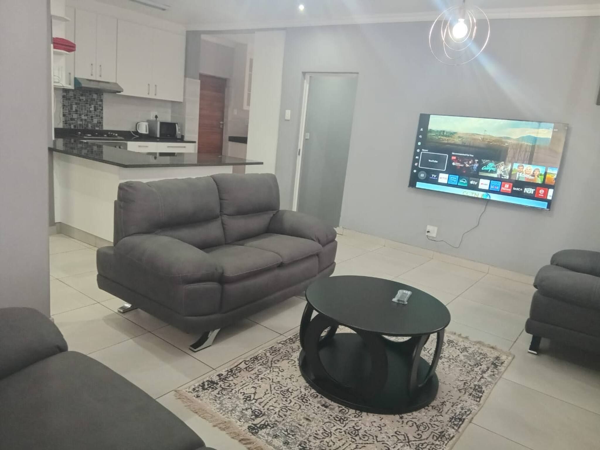 A living room with a grey sofa, a black coffee table, and a patterned rug.