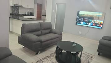 A living room with a grey sofa, a black coffee table, and a patterned rug.