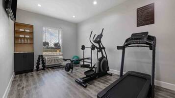 A home gym with a treadmill, elliptical, and weights.
