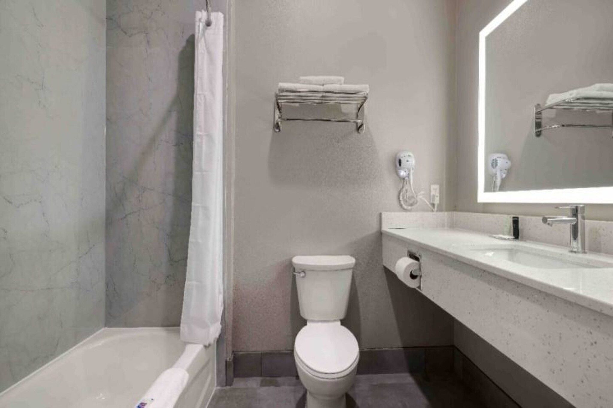 A bathroom with a bathtub, toilet, and a sink with a mirror.