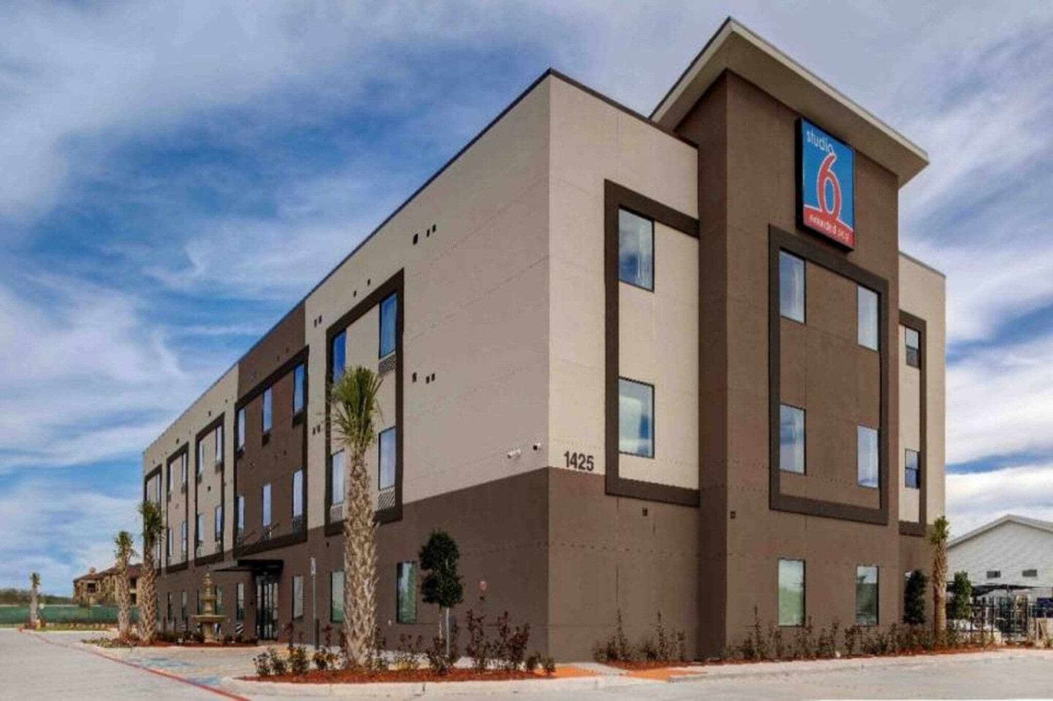 Un moderno edificio de hotel con techo plano, múltiples ventanas y un letrero que indica que es un hotel de 6 estrellas.